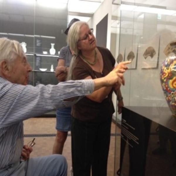 Zwei ältere Menschen schauen eine Vasenskulptur an