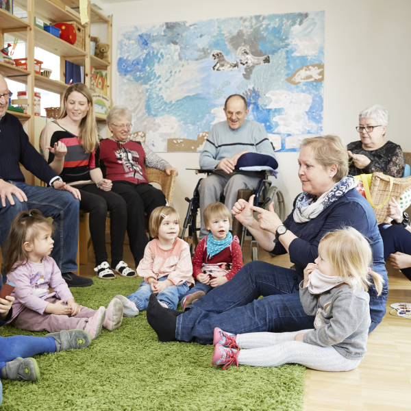 Kinder und ältere Menschen sitzen im Kreis