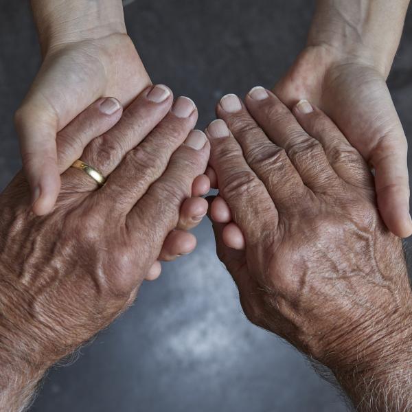 Hände einer jungen und einer älteren Person halten sich 