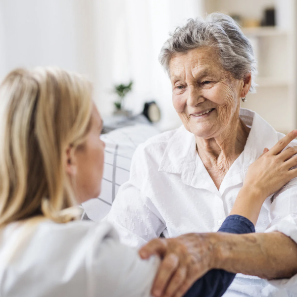 pflegerin und patientin schauen sich an, lachend, auf augenhöhe